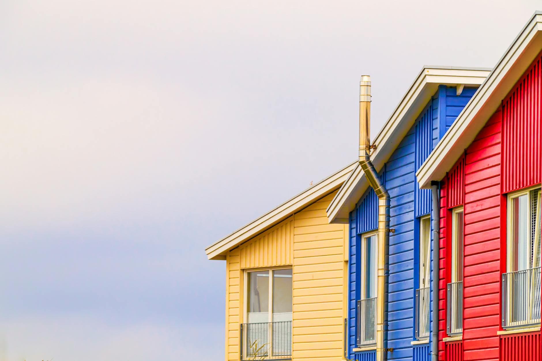 Vibrant red, blue, and yellow modern houses with clear sky backdrop, highlighting minimalist architecture.