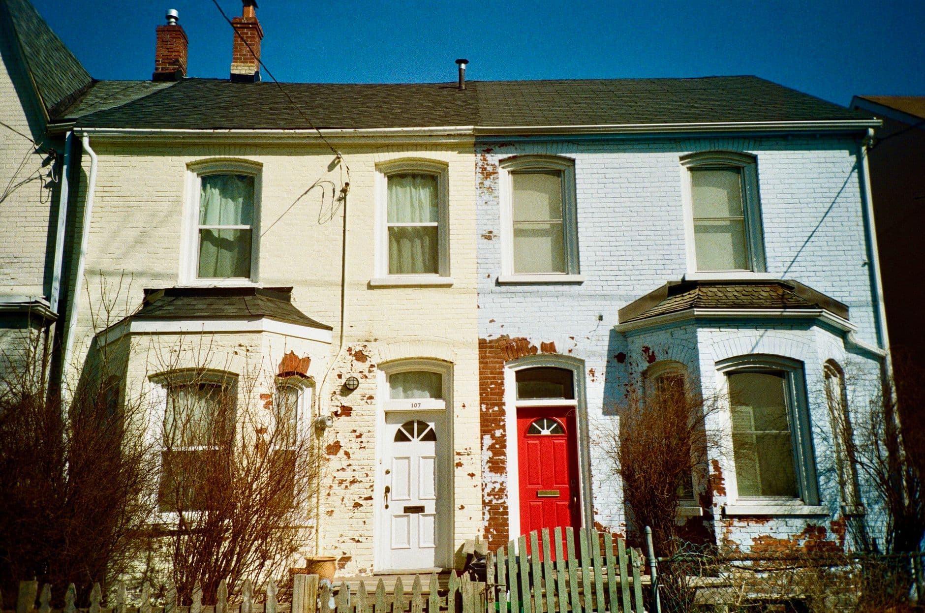 Colonial-style brick houses in Toronto with rustic charm, featuring distinct red and white doors.